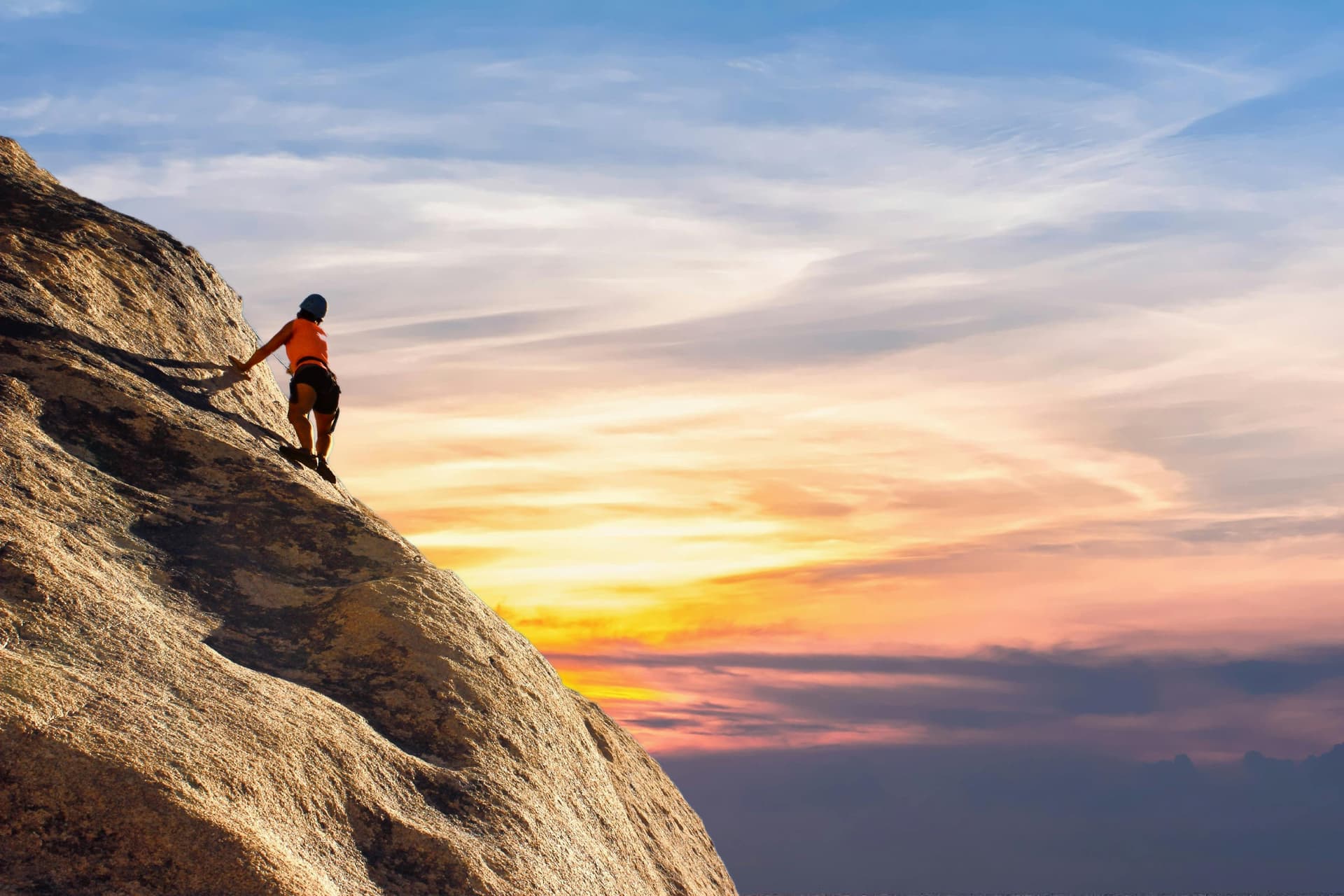 Un hombre escalando una montaña en el atardecer